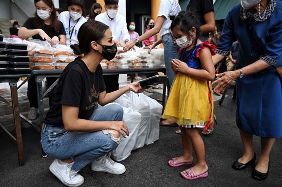 当地时间2021年6月14日，泰国曼谷，2020年泰国环球小姐冠军阿曼达·奥布丹（前左）在曼谷的一个贫民区向民众分发由米其林餐厅厨师制作的餐食。